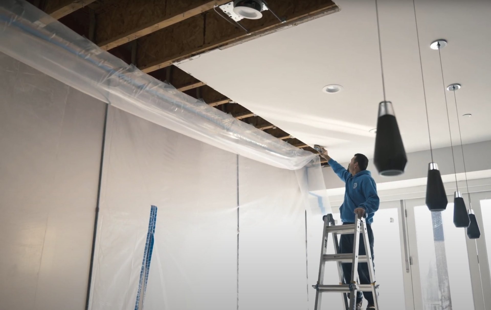 Water damage restoration professional covering ceiling and protecting area during emergency water damage response