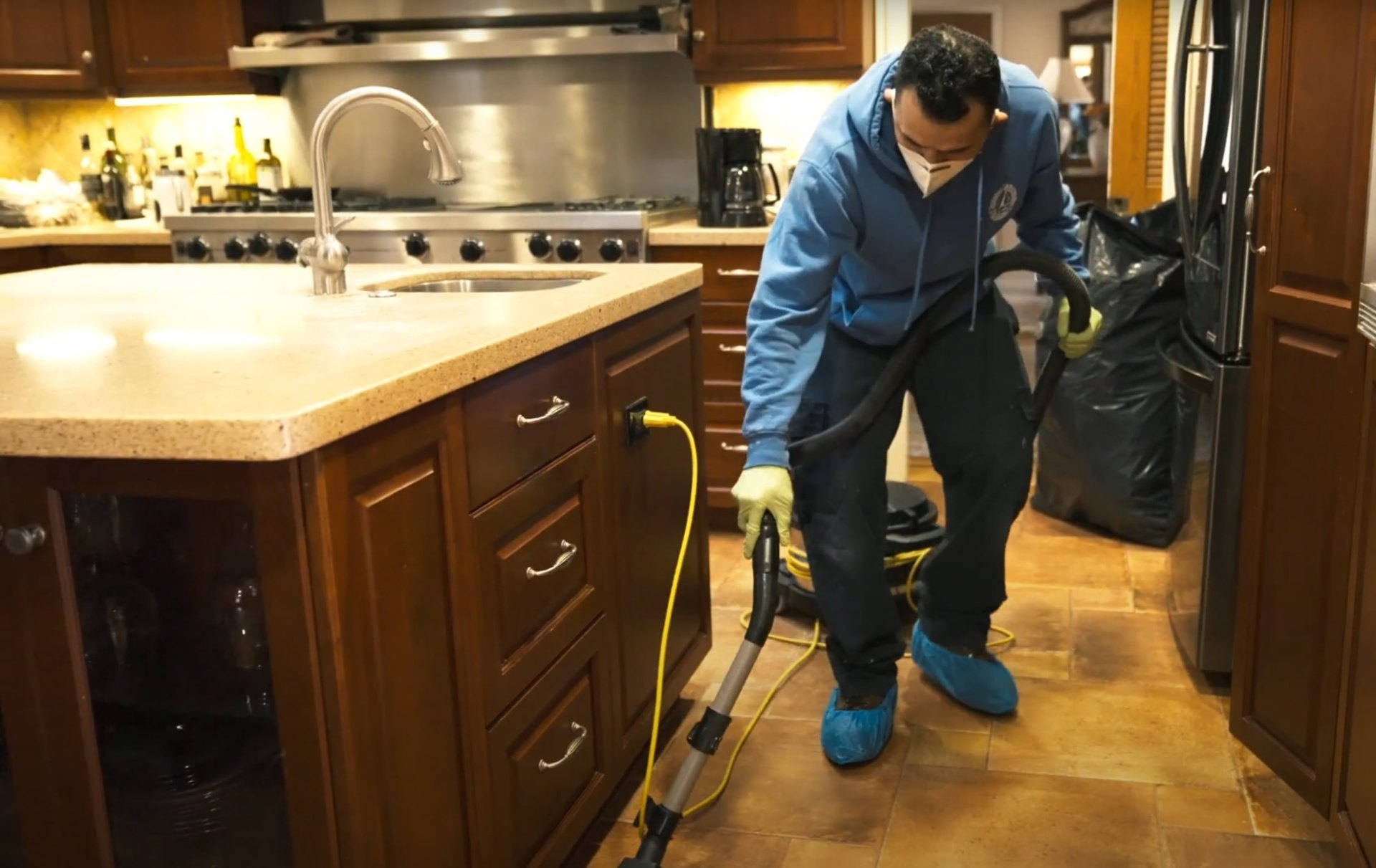 Water damage restoration specialist using professional equipment to extract water from kitchen flooring