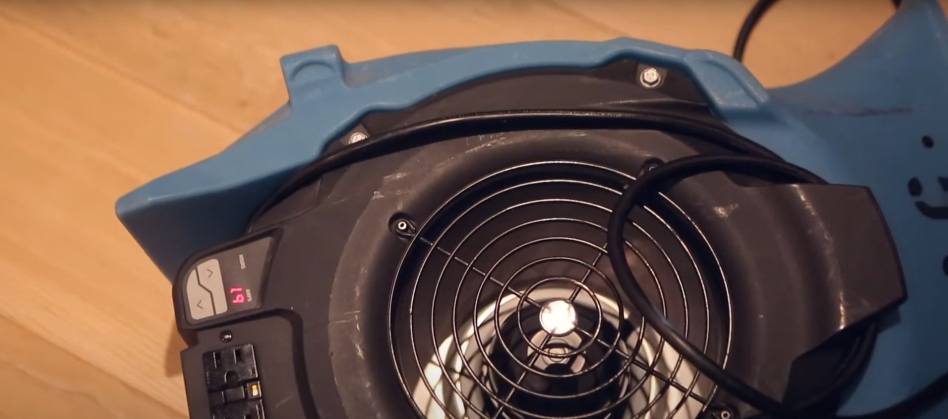 Close-up view of professional water extraction equipment showing air mover fan and control panel for water damage restoration