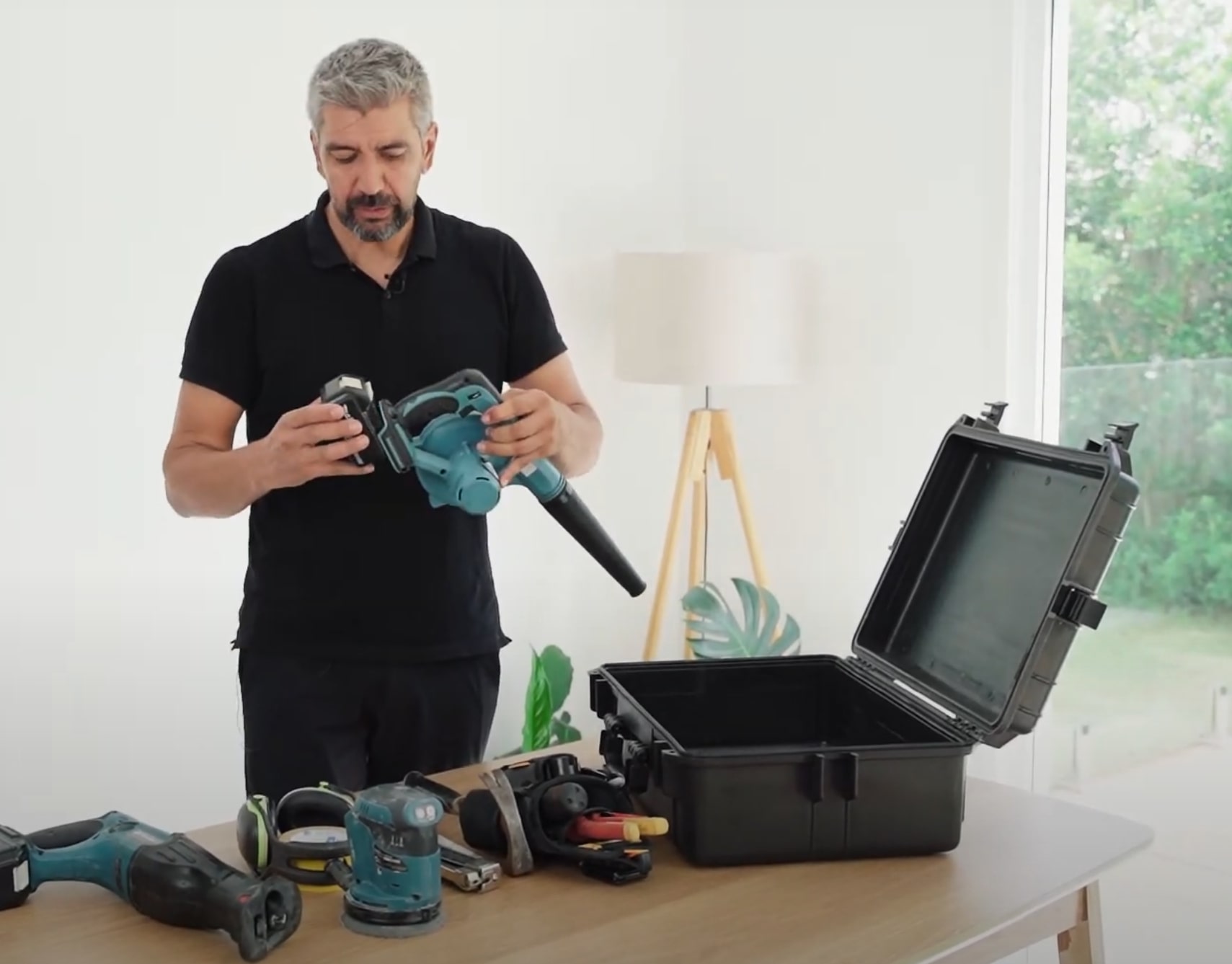 Professional water damage restoration technician examining handheld moisture detection equipment with toolbox of restoration tools