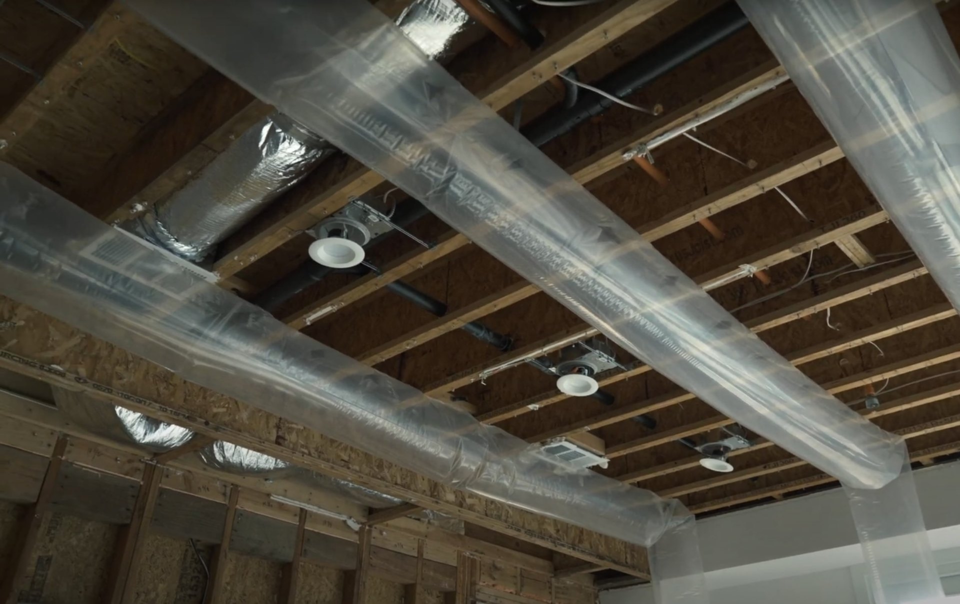 Exposed basement ceiling showing water damage with ductwork and structural elements visible during damage assessment